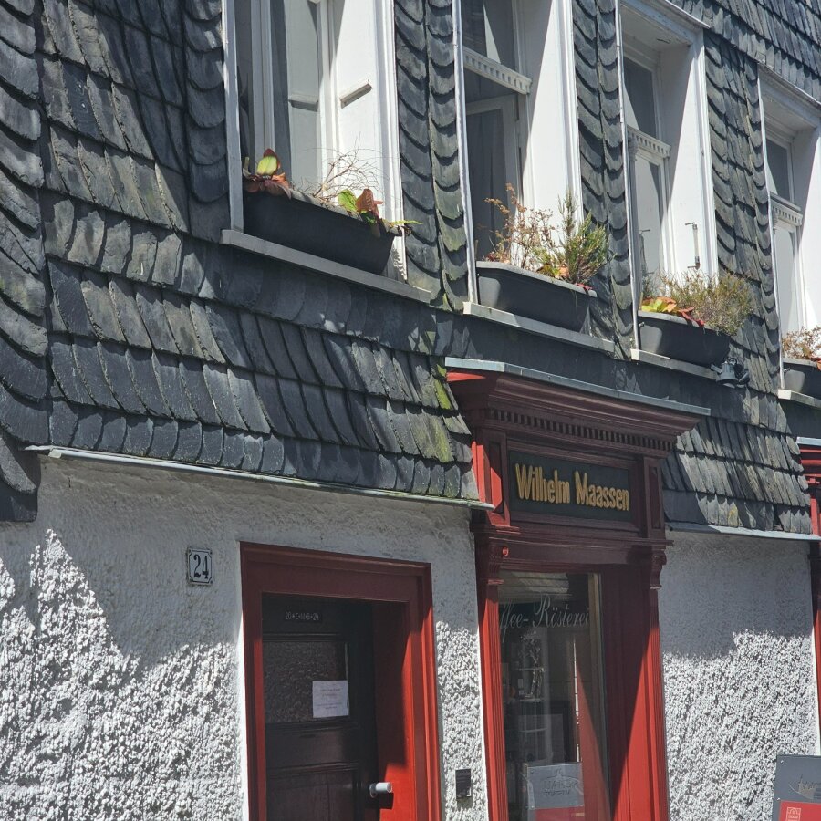 Slate facade with a red door and shutters in Monschau