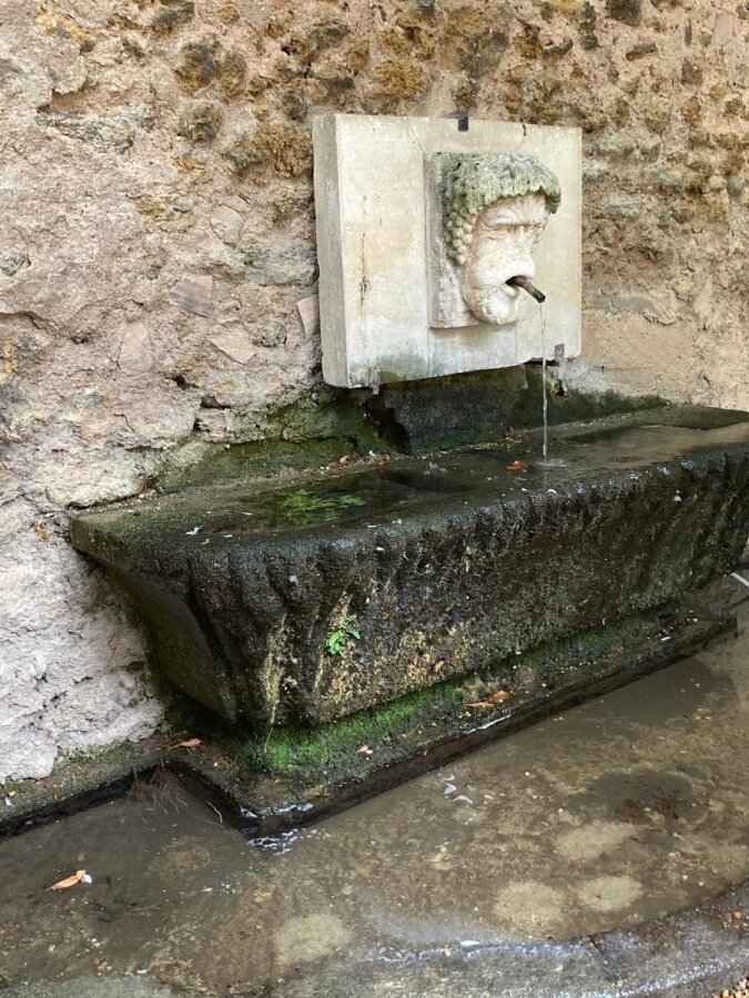 Old stone fountain with a mask head set in the wall