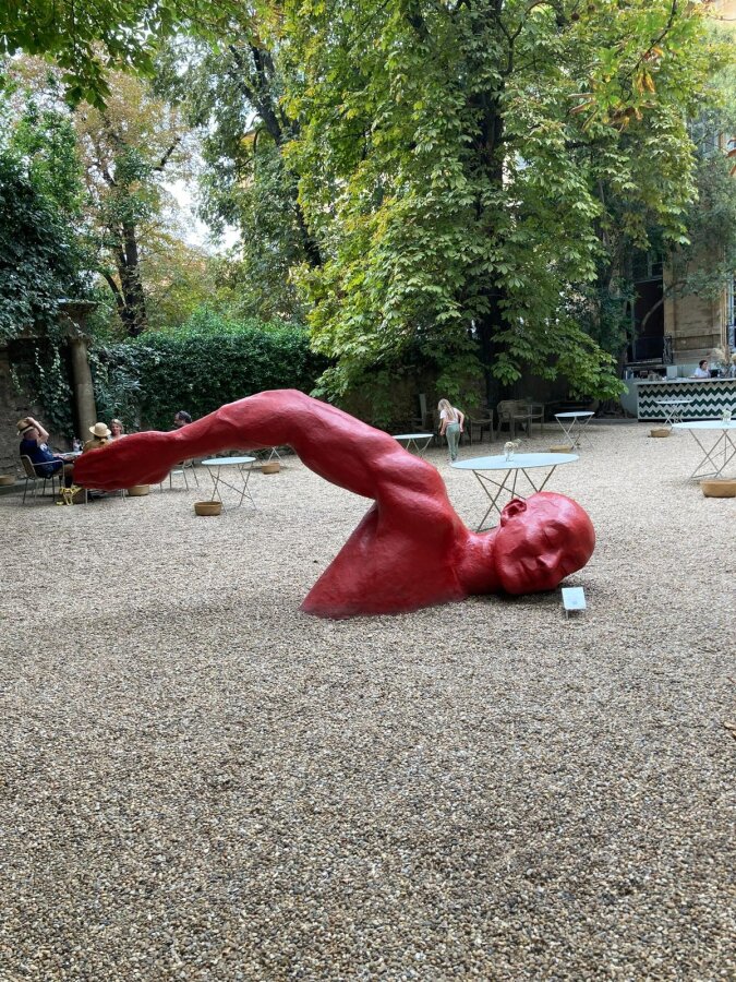 Red sculpture of a reclining figure in a park in Aix-en-Provence