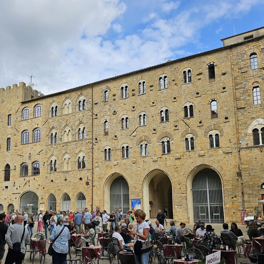 Large stone palazzo with cafe terraces on the square in Volterra