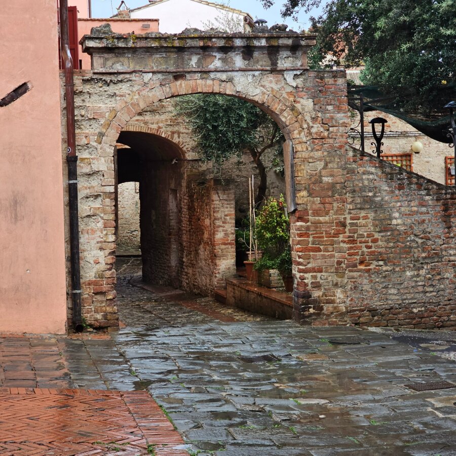 Brick gateway with wet cobbles after the rain in Certaldo Alto