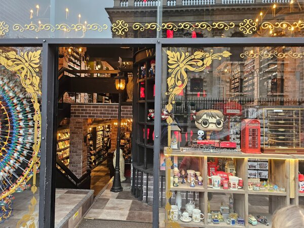 Window of a Harry Potter shop with wands, a red telephone box, mugs and a model train behind the glass.