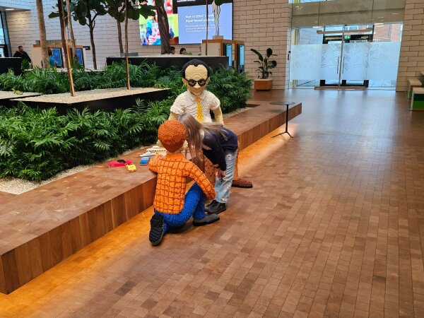 The bright entrance hall of LEGO House with trees and wooden benches