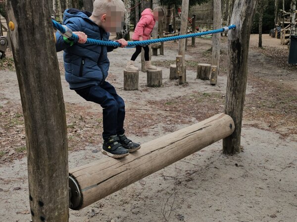 Child balancing along a tree trunk in the playground