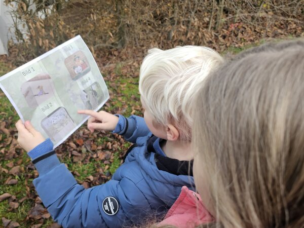 Child pointing at something on the photo scavenger hunt card