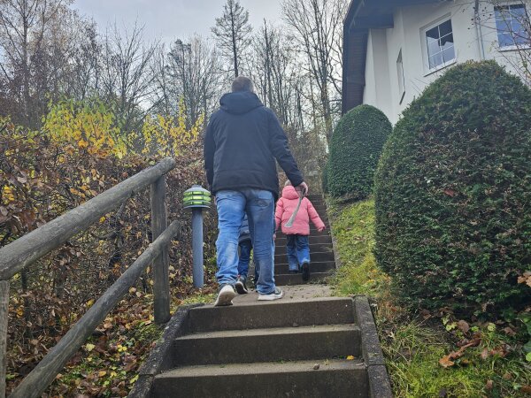 An adult and a child walking up the steps beside the cottage at Landal Salztal Paradies.