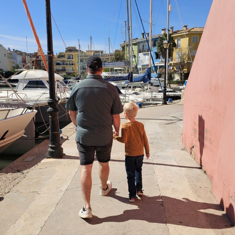 Adult and child walking along the marina of Port Saplaya