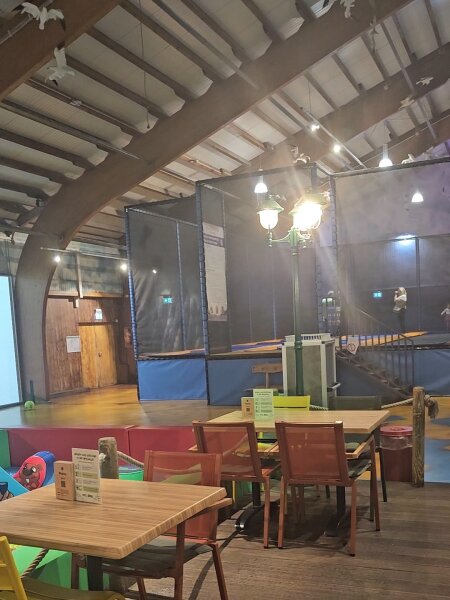 Trampolines behind netting and cafe tables in the indoor play hall