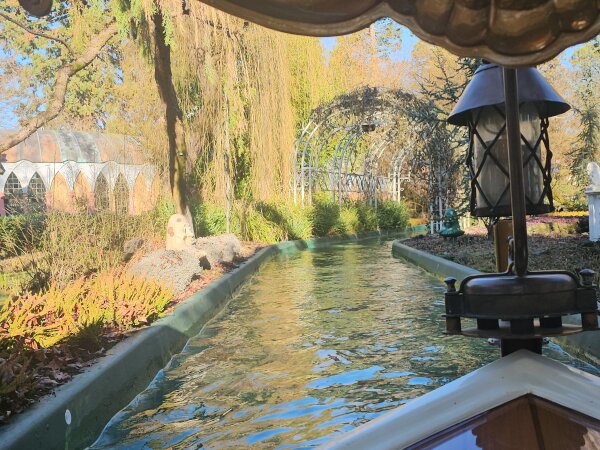 View from a boat on a water ride at Europa-Park, along a canal through a winter garden with a greenhouse.