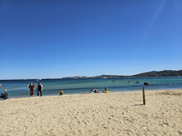 Plage de Port Grimaud met fijn zand, helder ondiep water met een boeienlijn en zeilboten in de baai