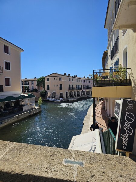 Kanaal in Port Grimaud met restaurantterrassen aan weerszijden en een arcade van bogen aan het eind