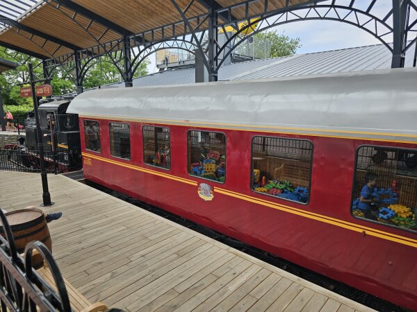 Red train carriage at a platform in Irrland, with coloured building blocks behind the windows