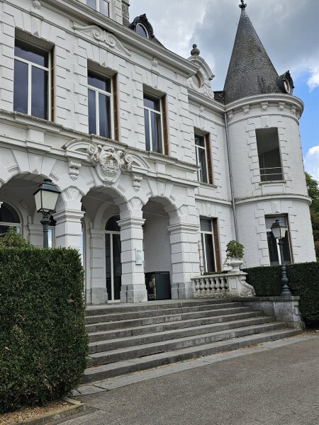 White château with a turret and a wide stone staircase at Domaine de Chevetogne