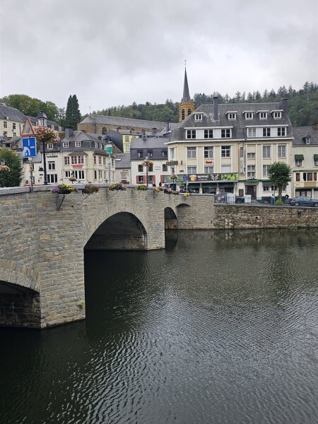 Stone arched bridge over the Semois with the houses and church tower of Bouillon behind it